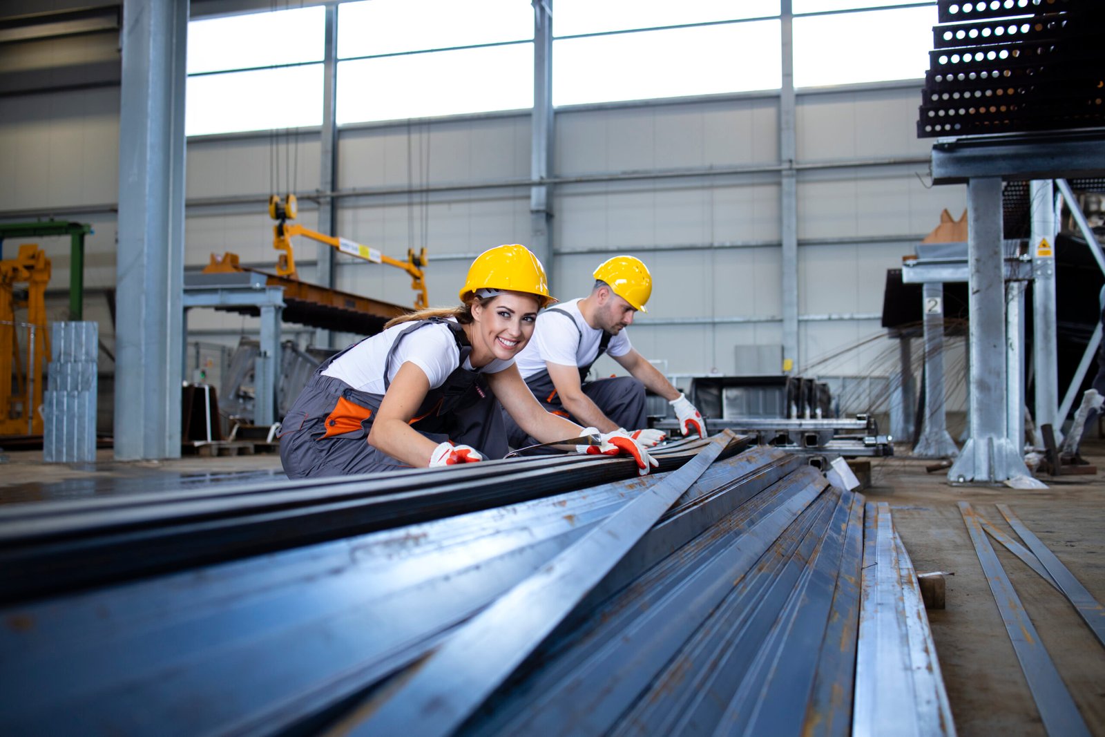 Home industrial workers working in factory hall with metal.